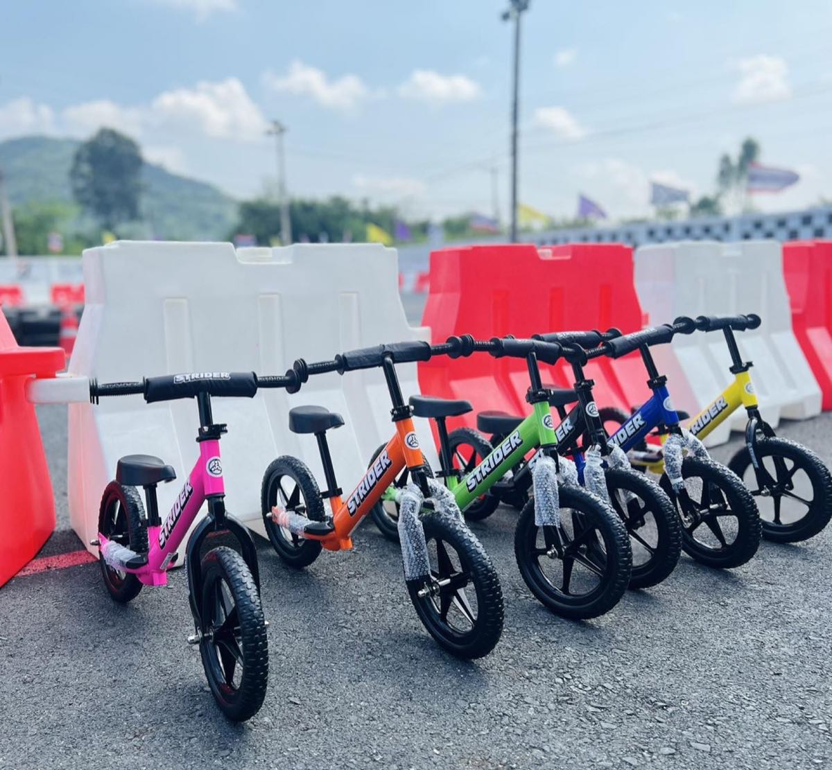 จักรยานทรงตัว Strider เรียงพร้อมใช้งานข้างแบริเออร์สนาม / Strider balance bikes lined up ready for use beside the track barriers