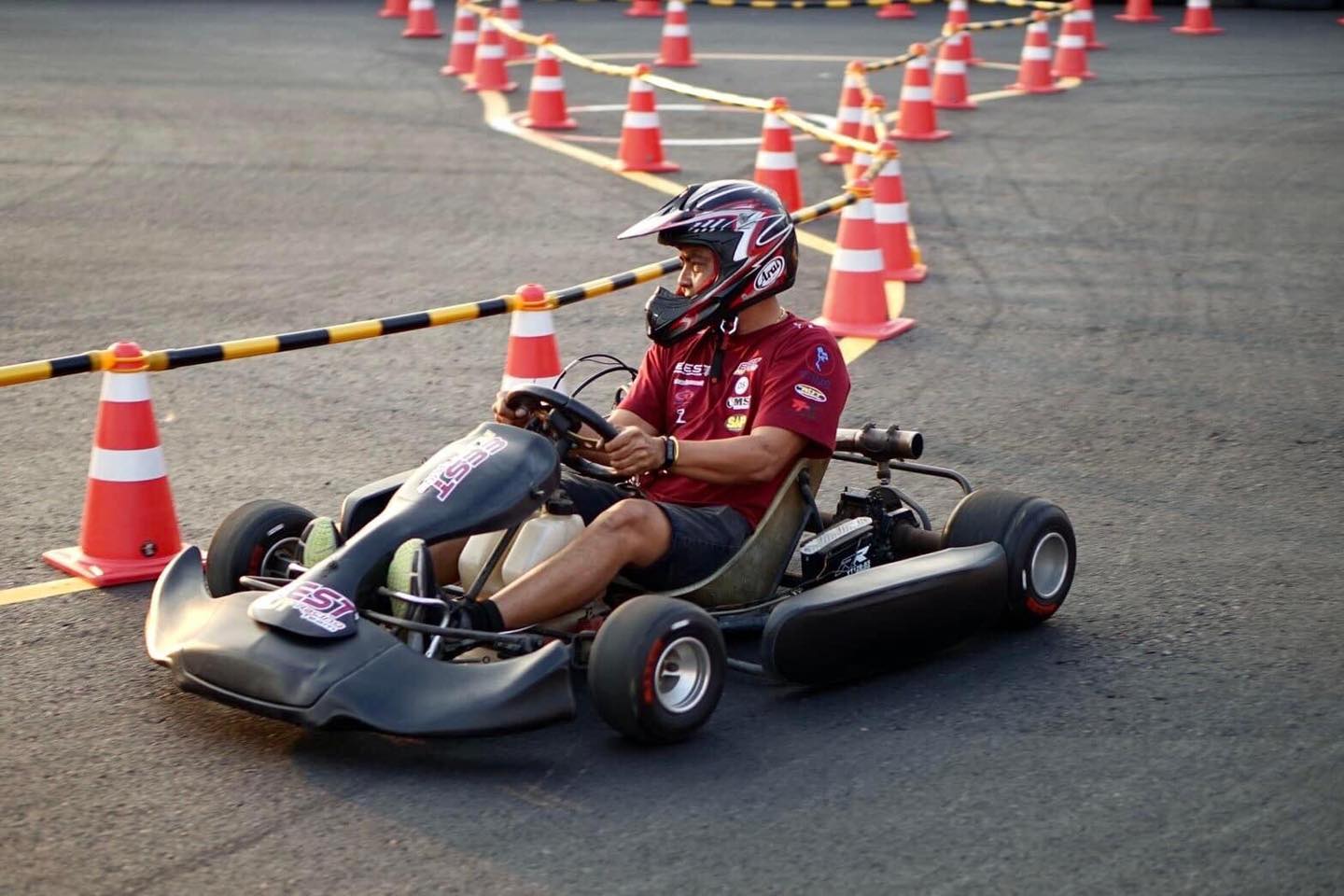 คนขับสวมหมวกกันน็อคขับโกคาร์ทบนสนาม EEST NJT / A helmeted driver at the wheel of a go-kart on the EEST NJT circuit