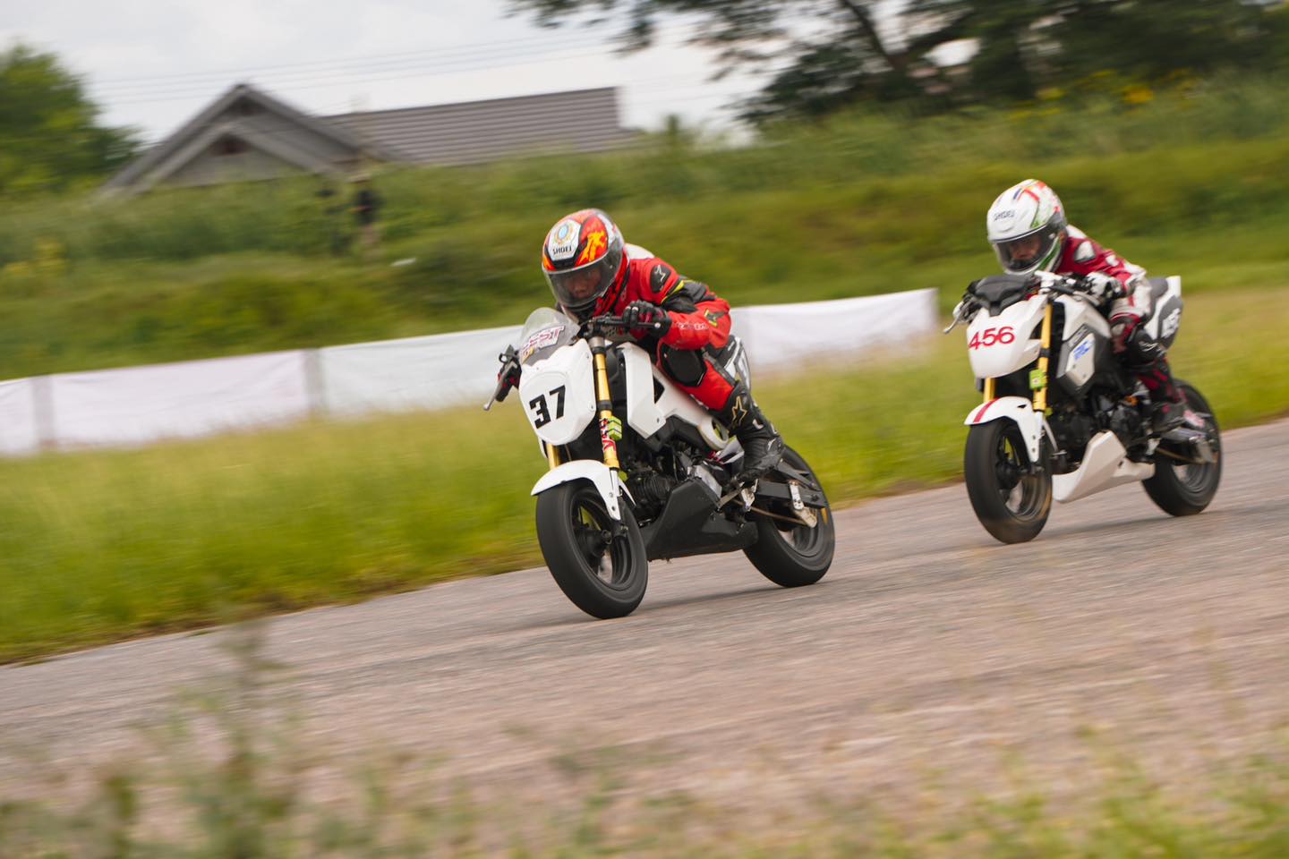Two mini-GP riders racing side by side on the circuit