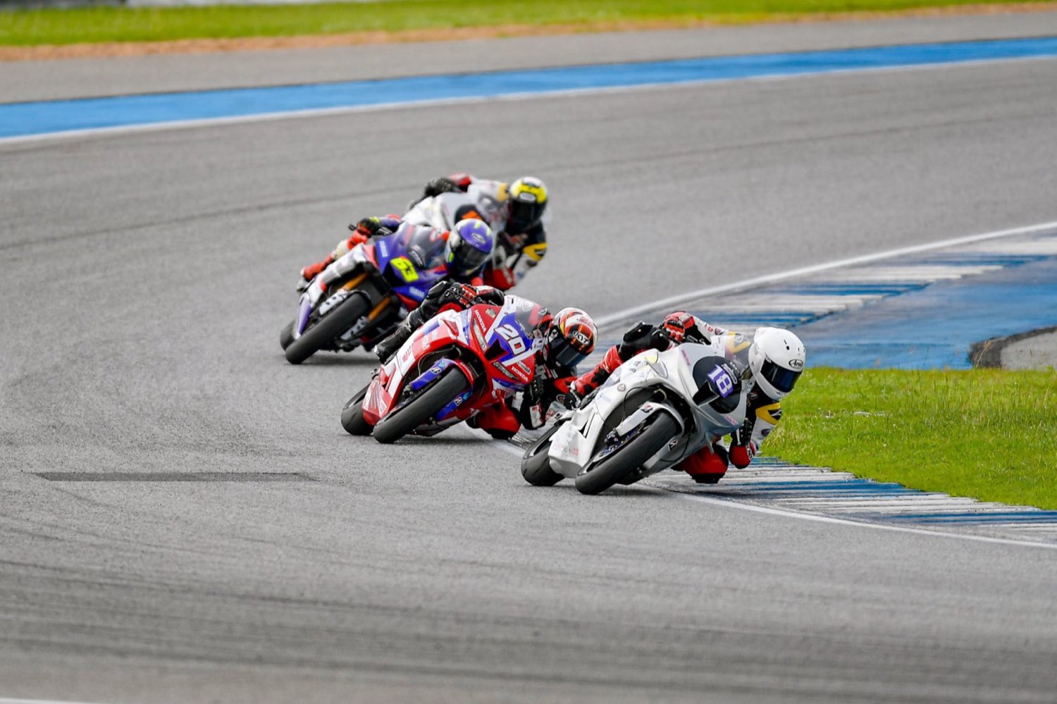 นักแข่ง EEST NJT นำกลุ่มเข้าโค้งในการแข่งขันทางเรียบ / An EEST NJT racer leading the pack through a corner in a road race