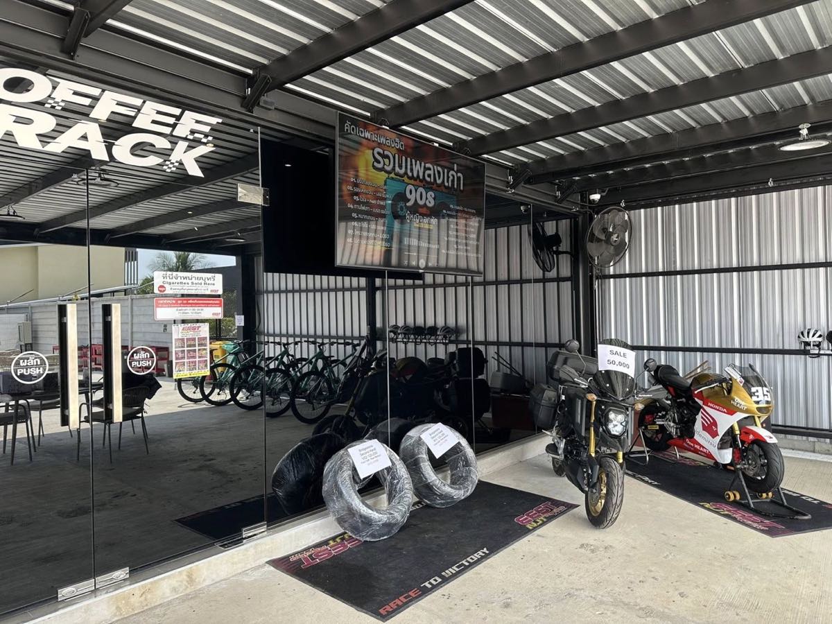 หน้าร้าน Coffee Track ริมสนาม พร้อมป้ายร้านและมอเตอร์ไซค์จอดโชว์ / The trackside Coffee Track storefront, with its sign and display motorcycles
