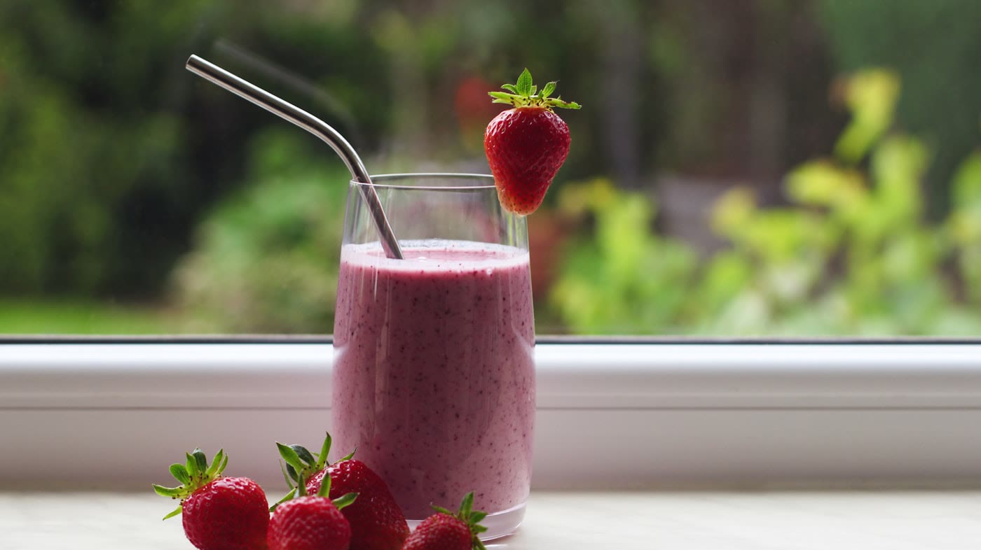 สตรอว์เบอร์รี่สมูทตี้ในแก้วใส เสิร์ฟพร้อมสตรอว์เบอร์รี่สด (ภาพประกอบ) / A strawberry smoothie in a clear glass with fresh strawberries (illustrative stock image)
